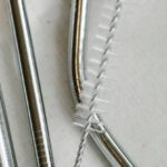 Sustainable Supply Chain - Top view composition of stainless steel straws and brush arranged on white bag on table