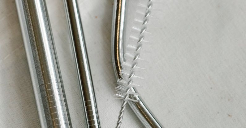 Sustainable Supply Chain - Top view composition of stainless steel straws and brush arranged on white bag on table