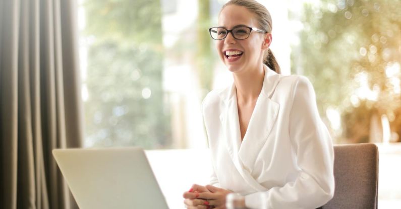 Career Pivot - Laughing businesswoman working in office with laptop