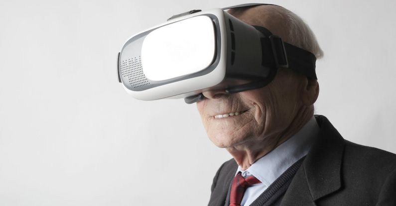 Virtual Reality Wellbeing - Smiling elderly gentleman wearing classy suit experiencing virtual reality while using modern headset on white background